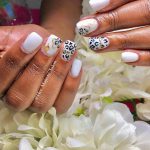 Short Gel White Nails With Cow Print Design Laying On White Flowers