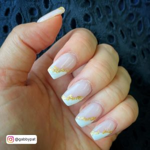 Short Nude Coffin Nails With White Tips And Gold Foils Against A Navy Background
