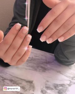 Short Nude Nails With White Tips Over Marble Surface