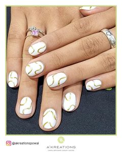 Short Round White Matte Nails With Golden Swrily Strips And Rings