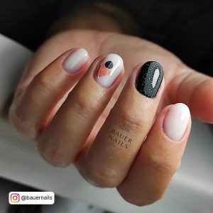 Short Rounded Milky White Nails With Shiny Black Glitter Nails And Black And Peach Design On A Feature Nail