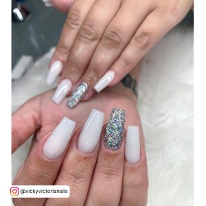 Short Simple White Acrylic Nails With Multicolored Glitters Over White Fur