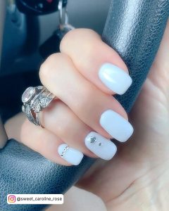 Short White Nails With Diamonds On A Steering Wheel