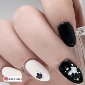 Simple Black And White Nails With Stamp Design On Ring And Middle Finger Holding Polish Bottle