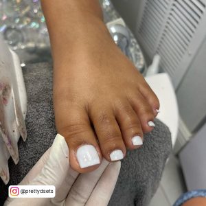 Simple White Acrylic Toe Nails Over Grey Towel