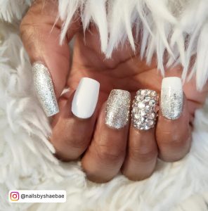 Square Tip Nails With One White Nail, One Silver Glitter Nail, One Silver Crystal Nail And One White And Silver Ombre Nail
