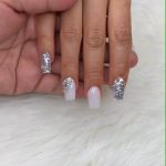 Square Tip Nails With Silver Glitter On Two Fingers And White Nails With A Silver Glitter Feature