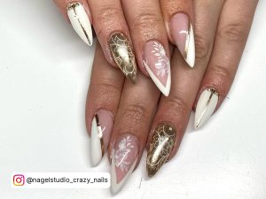 Stiletto Nude, White, And Golden Nails With Gold Stripes, White Tips And White Flowers