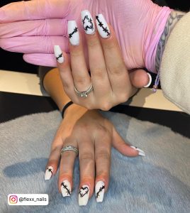 Thorny Black And White Acrylic Nails With Heart Design Over Grey Fur