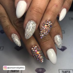 White Acrylic Nails With Diamonds And One Nail In Multi Colored Diamonds