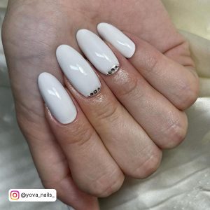 White Almond Nails With Cuticle Gems On Two Nails