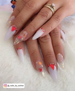White Almond Nails With Red Gems And Leaf Designs