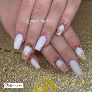White And Gold Ombre Nails With Gold Flakes Against A Glittery Background