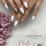 White Matte And Glitter Gold Almond Nails Near A Lilac Flower