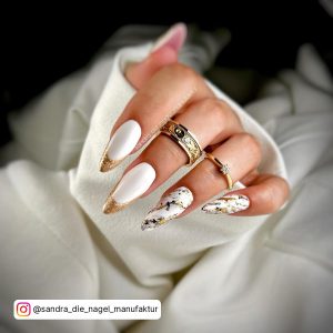 White Matte Stiletto Nails With Gold Gliter And Light Black Accent And Golden Rings