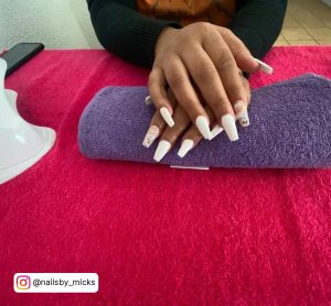 White Square Acrylic Nails With Gold Flakes On Purple Towel