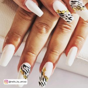 Zebra-Print Black And White Gel Nails With Gold Flakes Over White Surface