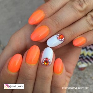 Bright Orange And White Nails With Diamonds On Ring Finger