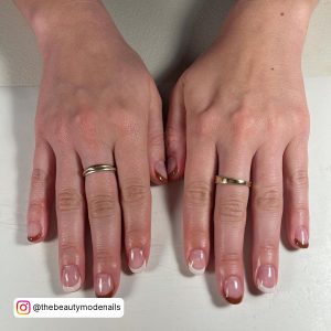 Brown And White French Tip Nails With Rings In One Finger