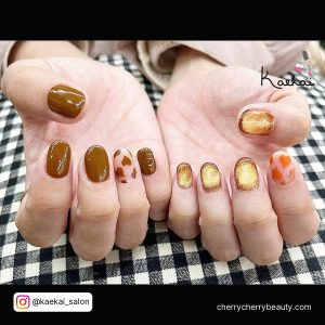 Brown Short Valentine Nails With A Nail With Small Brown Hearts, A Nail With Small Orange Hearts And Gold Nails