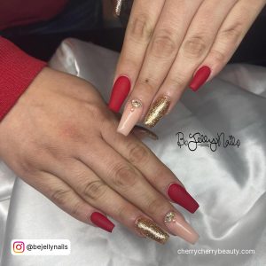 Coffin Baddie Red Acrylic Nails With Golden Glitter On Ring Finger