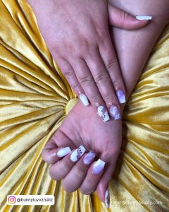 Gel Nails Purple And White On A Yellow Surface