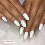 Glossy White Summer Acrylic Nails Over Patterned White Clothe.