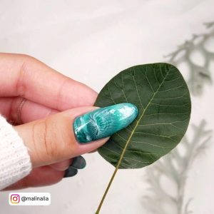 Green And White Nails Holding A Leaf