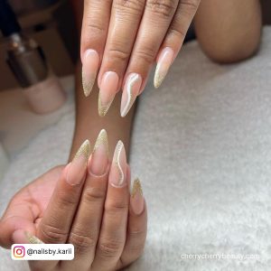 Long Almond Shape Nude, Gold Glitter Tip Nails With White Swirl Design