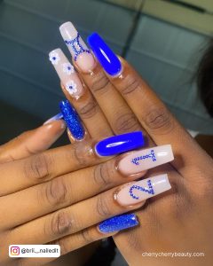 Long Blue And White Coffin Nails With Flower Design And 21 Written In Blue Gems