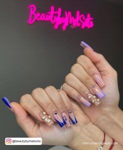 Long Square Tip Nails With Navy French Tip And Gold Dots With 21 Written In Navy On One Hand And Purple French Tips With Gold Dots And 21 Written In Purple On The Other Hand