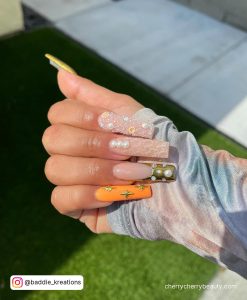 Long Square Tip Nude Nails With A Neon Orange Nail, A Chrome Gold Tip Nail, Glitter, Gold Stars And Pearls