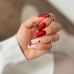 Long Square Tip Stain Red Nails With Two Milky White Nails With Small Black Hearts