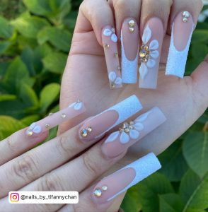 Long White Nails With Designs In Front Of Plants
