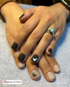 Matte Black Nails With White Design On Ring Finger