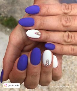 Nails Are Purple And White With Diamonds On One Finger