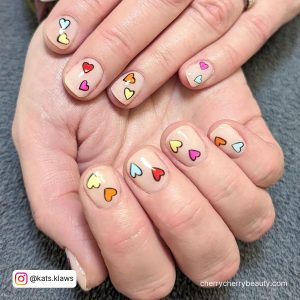 Nude Short Valentine Nails With Different Colored Hearts On The Nails