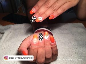 Orange White And Black Nails With Check Pattern On One Finger