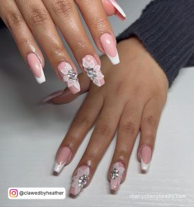 Pink And White Nails With Rhinestones And Flowers On Two Fingers