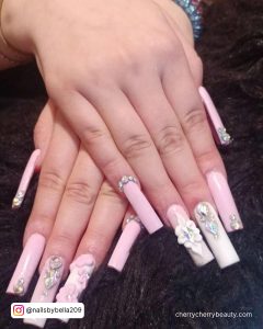 Pink And White Ombre Nails With Rhinestones On A Black Surface