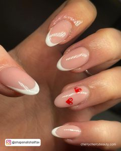 Round Tip French Tip Nails With Two Small Red Hearts On One Nude Nail