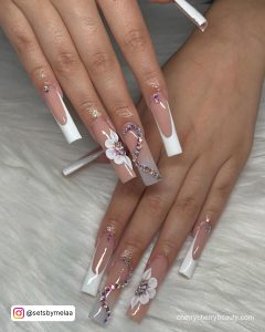 White Acrylics With Rhinestones And Flowers On A White Surface