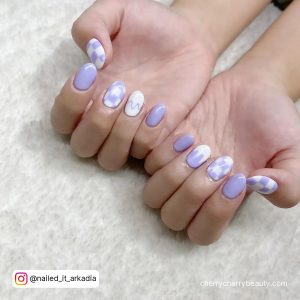 White And Purple Gel Nails On A White Surface