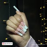 White Coffin Nails With Rhinestones In Front Of Fairy Lights