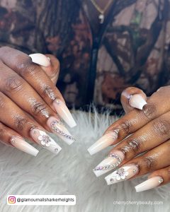 White Coffin Nails With Rhinestones On A White Surface