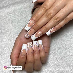 White French Tip Nails With Rhinestones On A White Surface