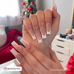White French Tips With Rhinestones In Front Of A Christmas Tree