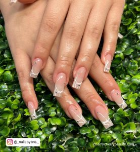 White Square Nails With Rhinestones On Top Of A Green Plant