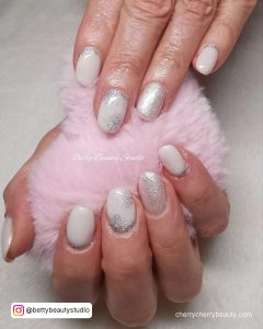 White With Silver Glitter Nails Holding A Pink Fur Ball