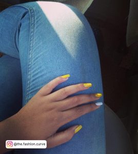 Yellow And White Nails Place On A Blue Jean